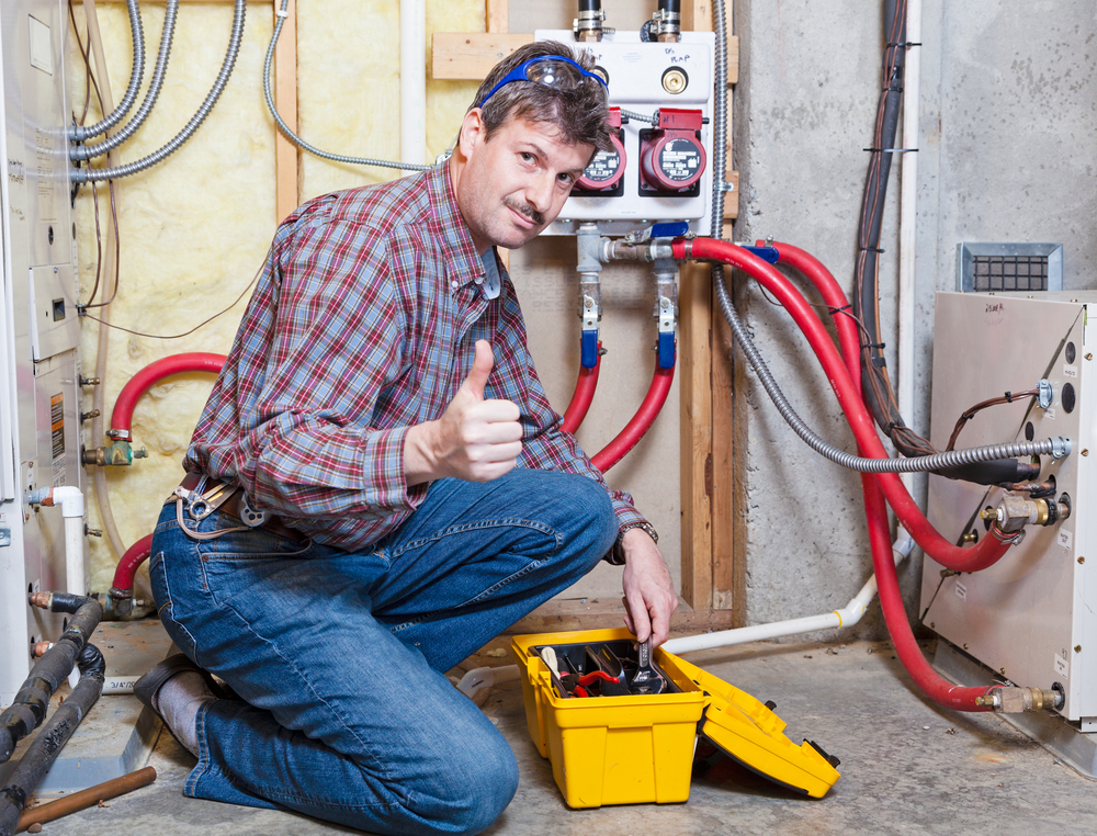 Happy handyman showing thumbs up while working on a furnace.